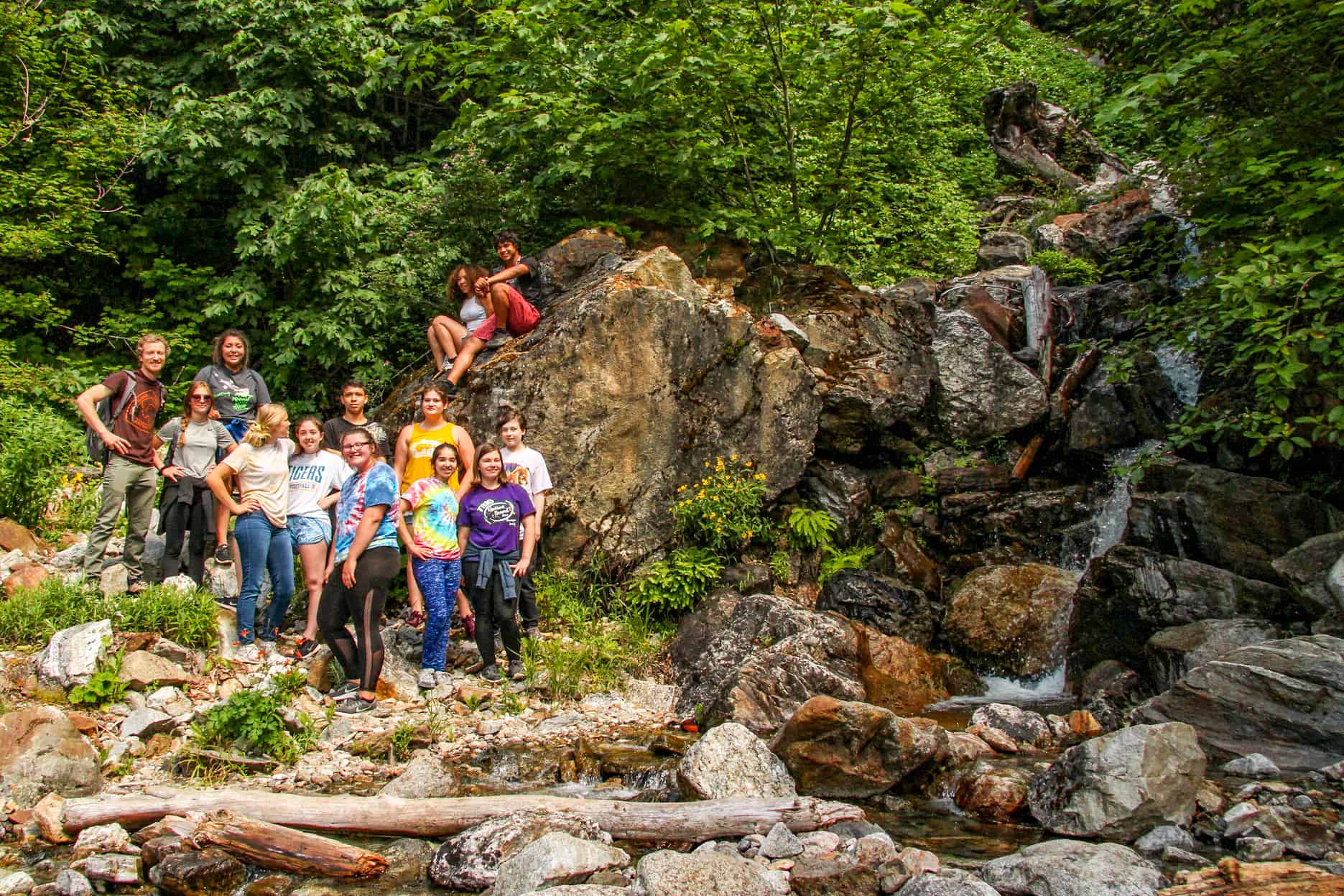 A group of youth pose near a waterfall in the North Cascades