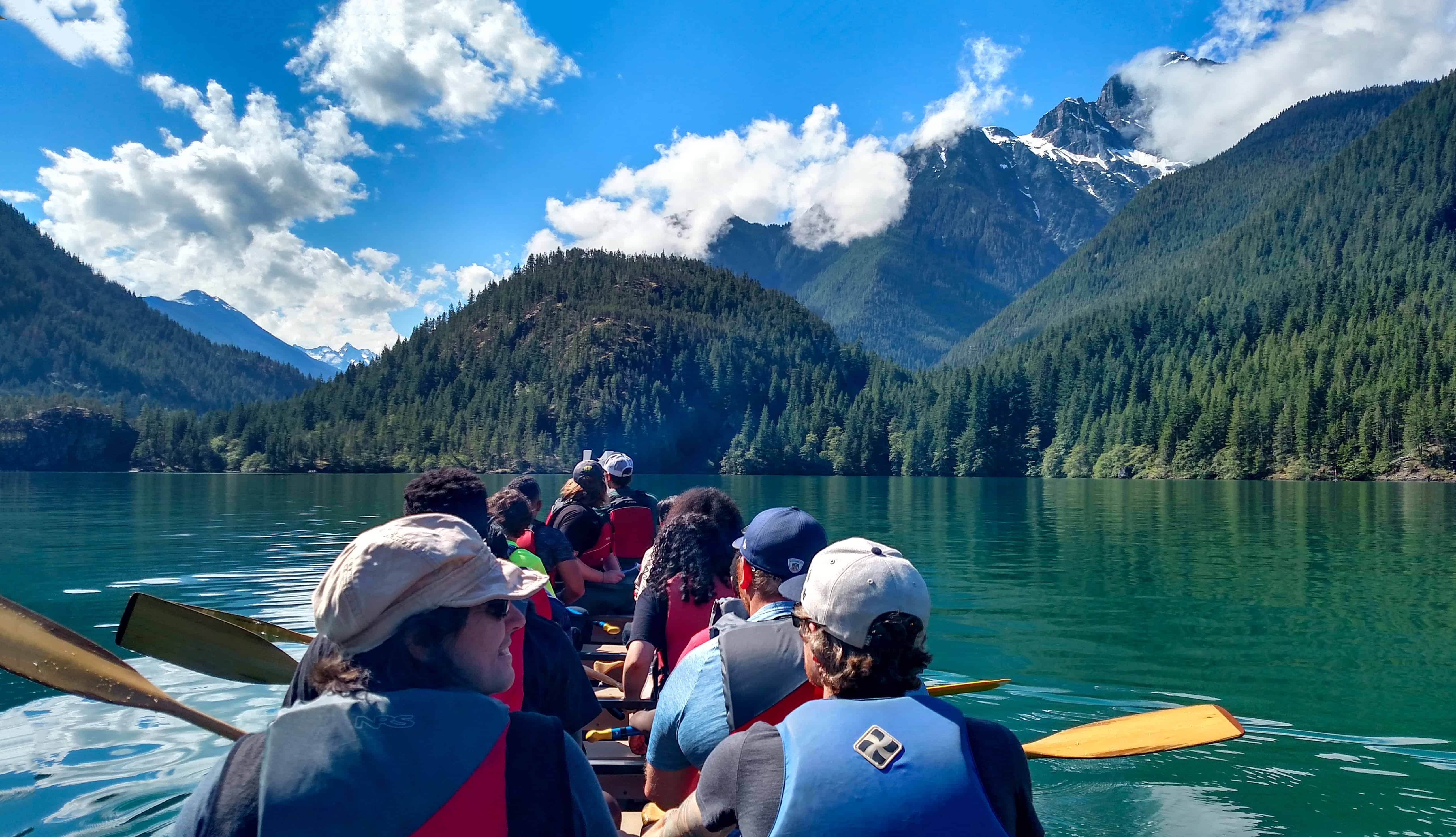 A group of adults taking in the beauty of Colonial Peak from a canoe on Diablo Lake