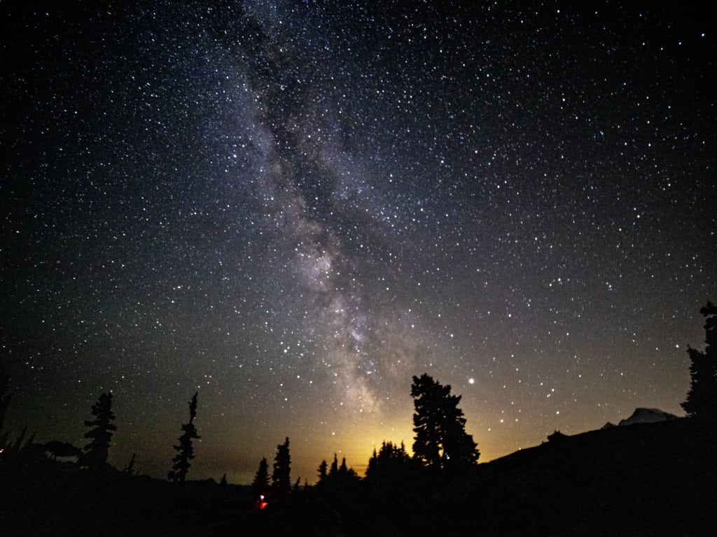 Night Sky from Artist Point with Milky Way shown above Mt Baker with coniferous tree silhouette on the skyline